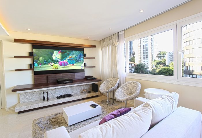 Agradável sala de estar em apartamento com tela e projetor Kreische Electronics.